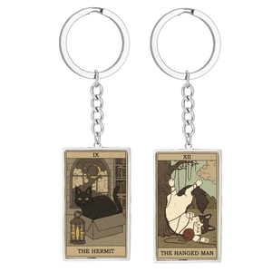 Detail of tarot cat keychains featuring The Hermit and The Hanged Man designs