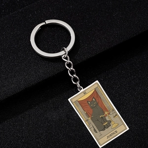 Close-up of Justice Tarot black cat stainless steel keychain on a dark background