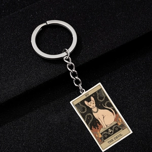 Close-up of silver tarot keychain featuring a Sphinx cat and The Devil art design