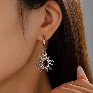 Macro detail of silver solar swirl earrings with polished metallic sunburst rays