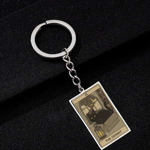 Detail of The Hermit tarot keychain featuring a black cat design on polished metal
