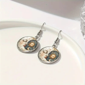 Handmade celestial drop earrings featuring sun, moon, and stars on a ceramic plate