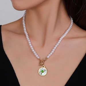 Detail of vintage faux pearl necklace featuring hummingbird pendant and gold toggle clasp
