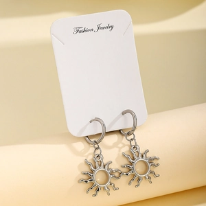 Silver stainless steel sun pendant hoop earrings on jewelry card with warm background