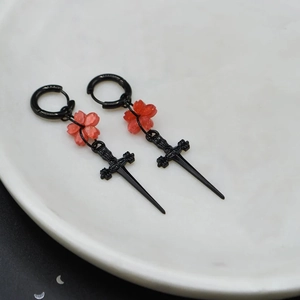 Boucles d'oreilles gothiques épée et fleur de cerisier rouge avec anneau noir sur marbre