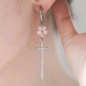 Détail de boucle d'oreille gothique avec pendentif épée argentée et fleur de cerisier