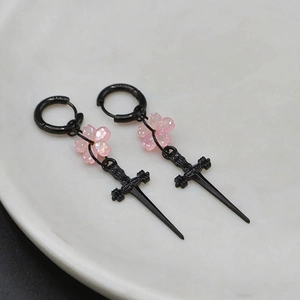 Détail de boucles d'oreilles gothiques en épée noire avec fleurs de cerisier