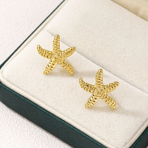 Boucles d'oreilles étoile de mer dorées texturées dans leur boîte à bijoux en velours