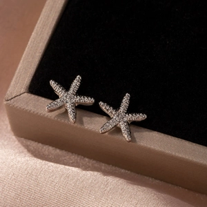 Vue macro des boucles d'oreilles étoile de mer argentées serties de cristaux blancs