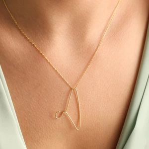Goldene Halskette aus Edelstahl mit Kleiderbügel-Anhänger an einem Model mit V-Ausschnitt
