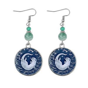 Détail des boucles d'oreilles ethniques avec perles vertes et pendentif loutre peinte
