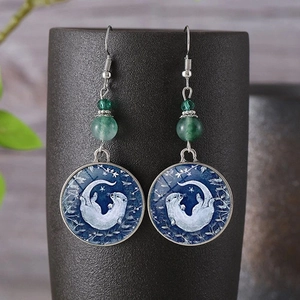 Boucles d'oreilles bohèmes loutre en verre avec perles vertes sur un vase en céramique