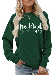 Detail of Be Kind hand-written text and braille print on dark green crewneck sweatshirt