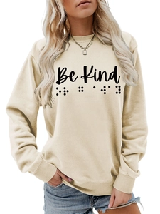 Detailed shot of Be Kind print and braille dots on cream crewneck sweatshirt fabric