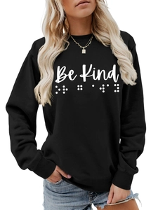 Detail of Be Kind text and braille print on black long-sleeve crewneck sweatshirt