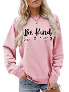 Detail of pink sweatshirt featuring Be Kind lettering and unique braille dot print