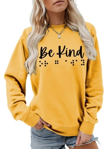 Detail of Be Kind text and Braille print on yellow long-sleeved cotton sweatshirt
