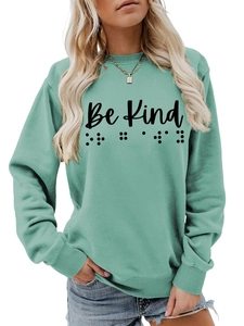 Detail of Be Kind text and braille print on sage green crewneck cotton sweatshirt