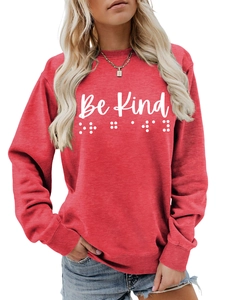 Close-up of Be Kind lettering and braille dots on a soft red crewneck sweatshirt