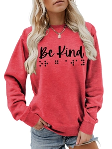 Detail of red crewneck sweatshirt featuring Be Kind text and braille dots art
