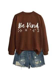 Detail of Be Kind print and braille dots on deep brown crewneck long sleeve sweatshirt