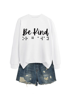 Close-up of white Be Kind sweatshirt with braille print paired with frayed denim shorts