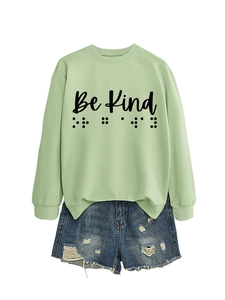 Detail of mint green Be Kind crewneck sweatshirt with braille text design and denim shorts