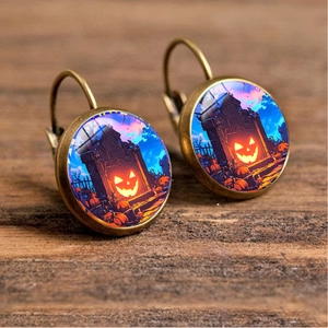 Macro shot of Halloween drop earrings with pumpkin and tombstone glass cabochon