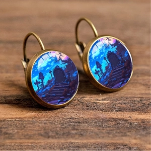 Detailed view of vintage bronze Halloween earrings featuring spooky graveyard illustrations