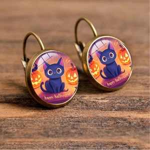 Detail of Halloween drop earrings with black cat and pumpkin motifs on wood background