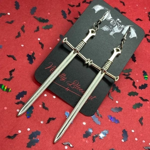 Detail of silver sword pendant earrings with gothic design on a black display card