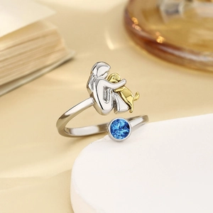 Detail eines silbernen Rings mit Mädchen das einen goldenen Hund hält und blauem Stein