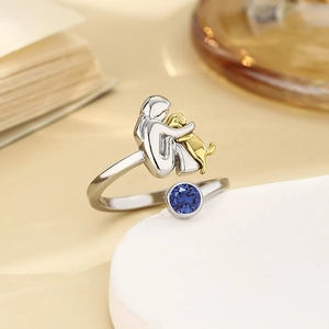 Nahaufnahme Ring mit silbernem Mädchen, goldenem Hund und tiefblauem Geburtsstein