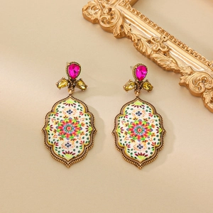 Detail of vintage bohemian earrings with pink droplet gems and painted floral patterns