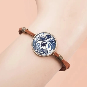 Vintage bronze bracelet featuring blue bird porcelain style charm on brown suede cord