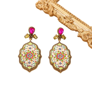 Macro view of vintage style earrings with enamel mandala flower and red drop stones