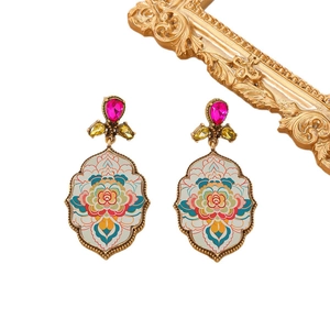 Close-up of vintage flower pattern earrings with colorful gemstones on a white background