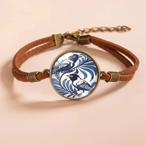 Detail of vintage bronze bracelet with blue porcelain style bird and flower glass cabochon