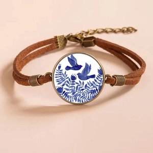 Macro detail of retro bronze bracelet with blue porcelain bird gem and brown cord