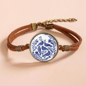 Detailed macro view of vintage bronze bracelet with blue bird glass cabochon and brown cords