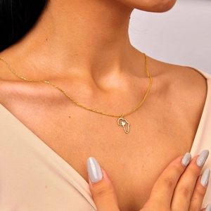 Gros plan du collier carte Afrique doré avec pendentif cœur porté par un mannequin