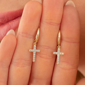 Golden cross hoop earrings with sparkling rhinestones worn by a model in a close-up view