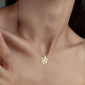 Gros plan d'un collier pendentif flocon de neige doré porté au cou pour Noël