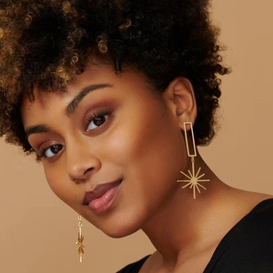 Detail of elegant gold tassel earrings with octagonal star pendant worn by a model