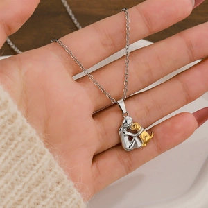 Titanium steel necklace with silver figure and gold puppy pendant shown on a hand