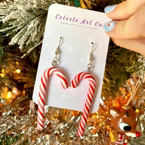Christmas candy cane earrings with red and white resin swirls on a festive background
