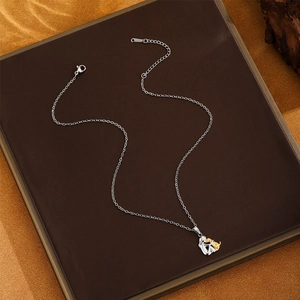 Detail of silver chain necklace featuring a gold and silver dog pendant with lobster clasp
