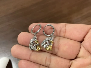 Macro detail of two-tone gold and silver girl hugging dog charm hoop earrings