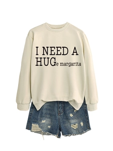 Flat lay of cream crewneck sweatshirt with I NEED A HUGe margarita text and denim shorts