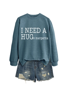 Close-up of I NEED A HUGe margarita slogan on grey blue sweatshirt fabric